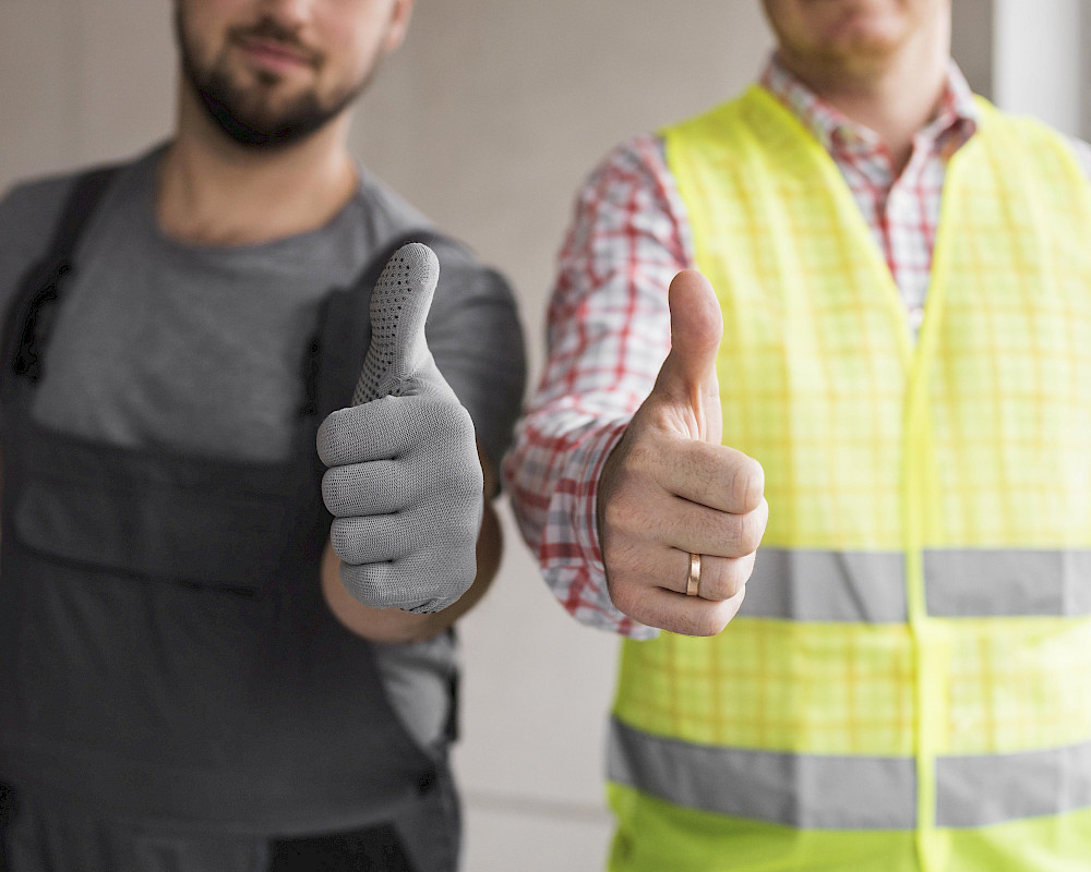 Zwei vertrauenswürdige Facharbeiter mit Daumen hoch nach erfolgreicher Betonsanierung mit sicheren Betonflächen zum Schutz der Immobilie