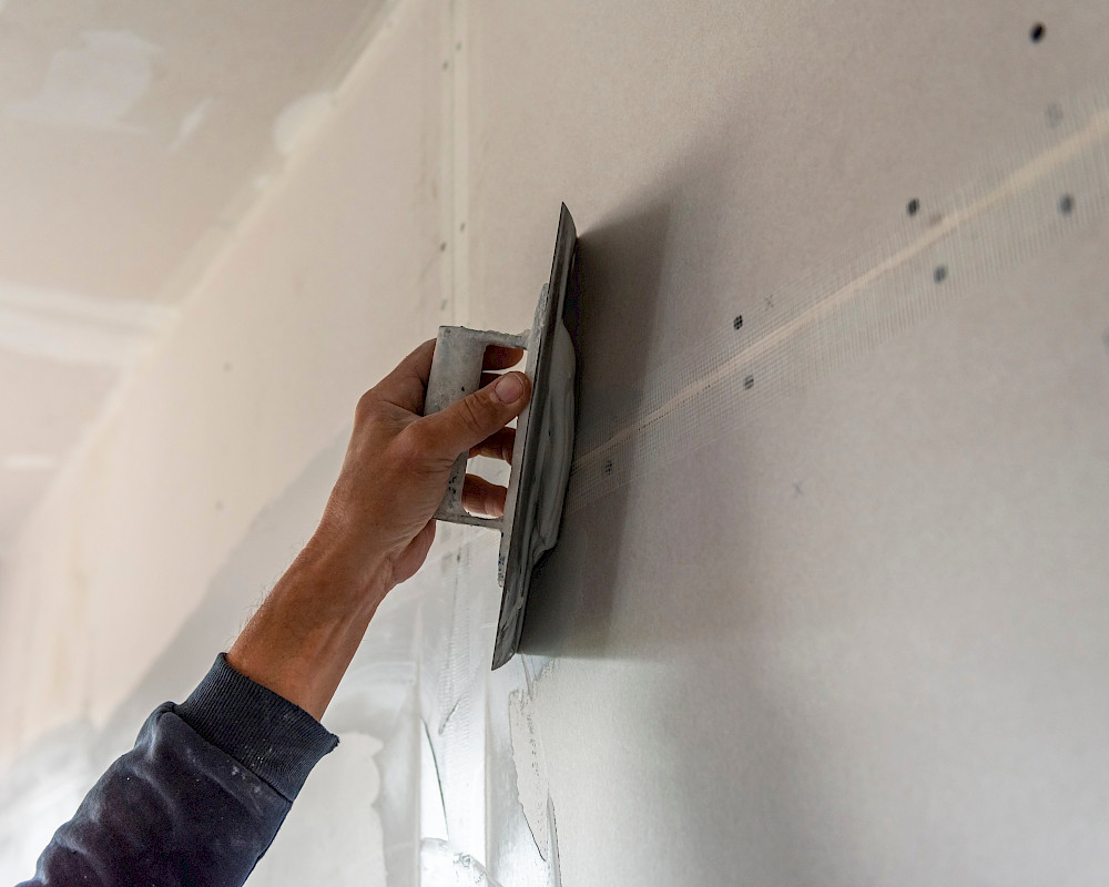 Profi von MaNos Abdichtungstechnik in Hamburg saniert Wand mit Spachtel nach erfolgreicher Schimmelbekämpfung